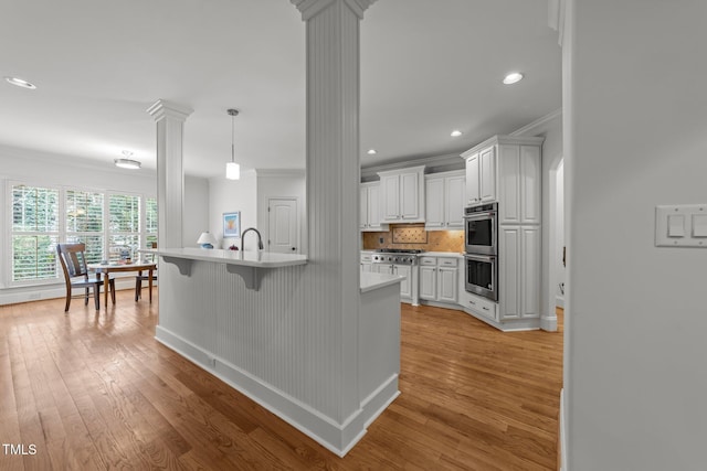 kitchen featuring light countertops, light wood-style flooring, and decorative columns