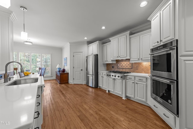 kitchen with ornamental molding, a sink, tasteful backsplash, stainless steel appliances, and light countertops