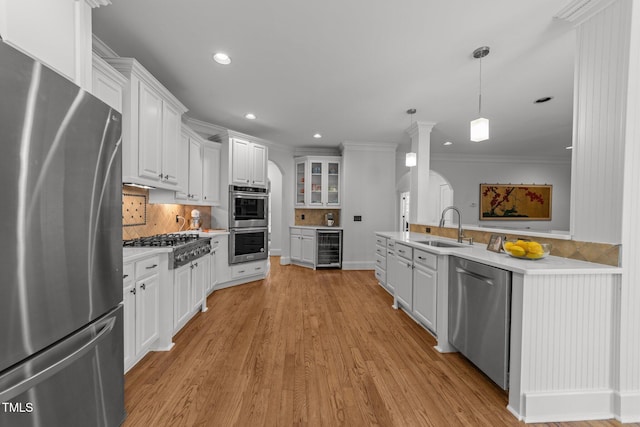 kitchen with wine cooler, white cabinets, stainless steel appliances, and a sink