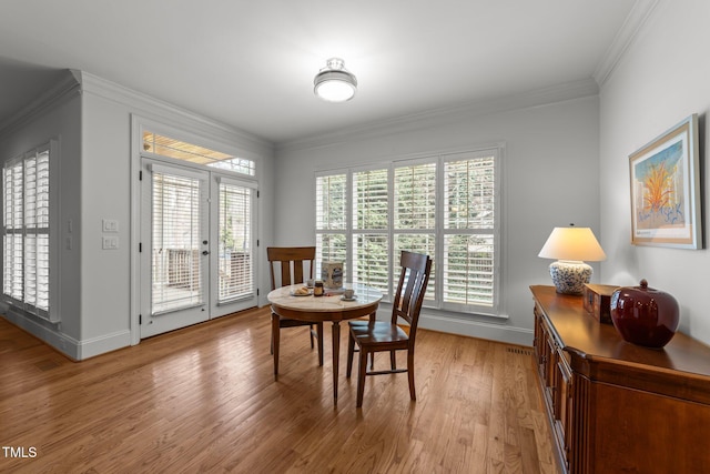 dining room featuring light wood finished floors, baseboards, a wealth of natural light, and ornamental molding