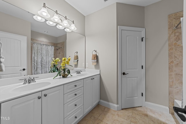 bathroom featuring double vanity, tiled shower, baseboards, and a sink