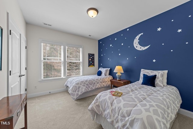 carpeted bedroom with an accent wall, baseboards, and visible vents