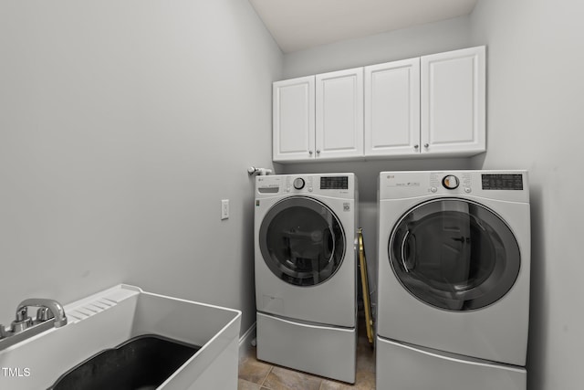 laundry room with a sink, baseboards, cabinet space, and washing machine and dryer