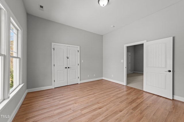 unfurnished bedroom featuring a closet, baseboards, visible vents, and light wood finished floors