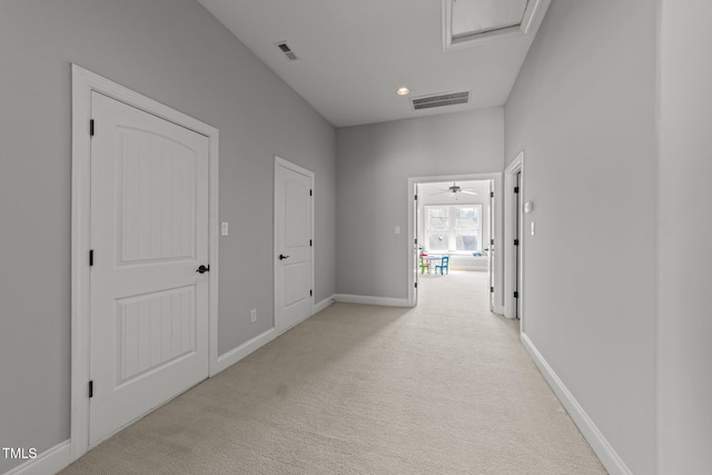 corridor featuring visible vents, baseboards, and light colored carpet