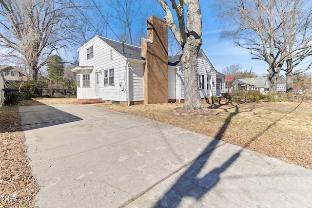 view of home's exterior with a shingled roof, entry steps, fence, and a chimney