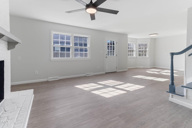 unfurnished living room featuring stairs, visible vents, a fireplace, and wood finished floors