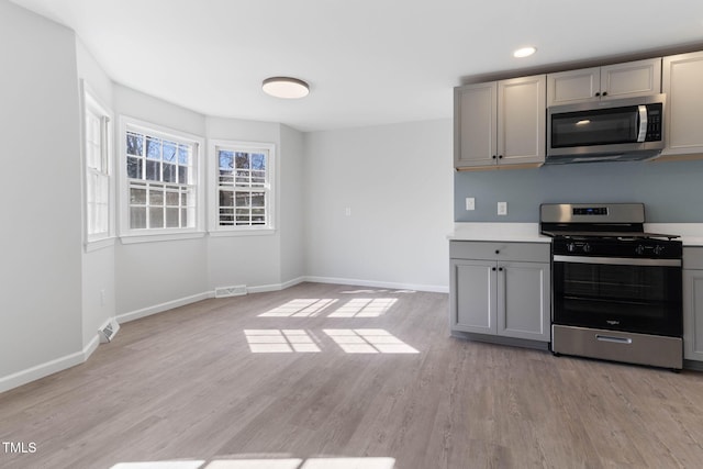 kitchen featuring light wood-type flooring, gray cabinets, visible vents, and stainless steel appliances