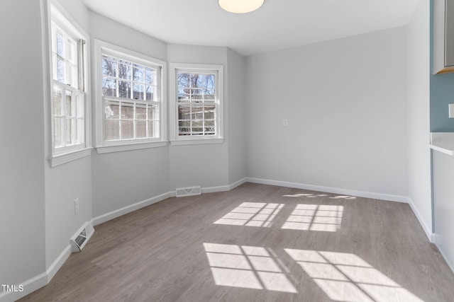 spare room featuring visible vents, baseboards, and wood finished floors