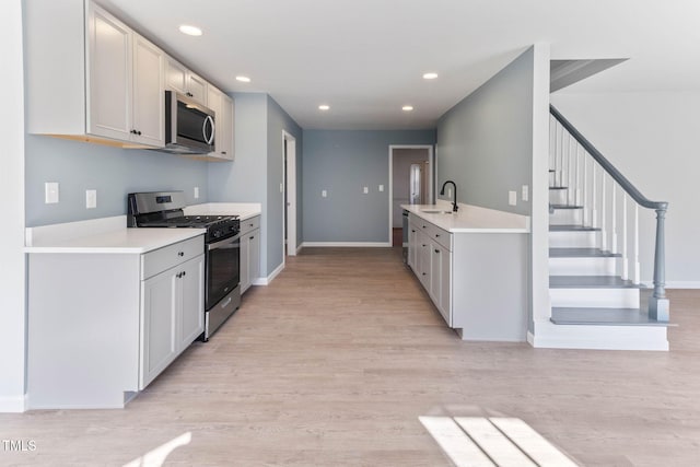 kitchen with light wood-type flooring, appliances with stainless steel finishes, light countertops, and recessed lighting