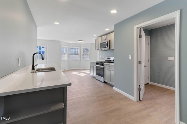 kitchen featuring baseboards, light wood-style flooring, appliances with stainless steel finishes, open shelves, and a sink