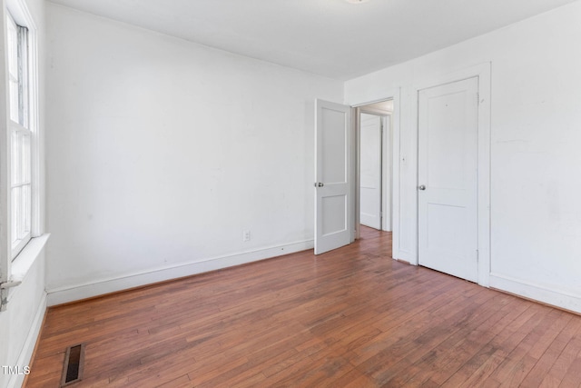 unfurnished room with hardwood / wood-style flooring, baseboards, and visible vents