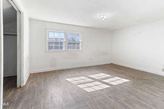 unfurnished bedroom featuring a textured ceiling, baseboards, and wood finished floors