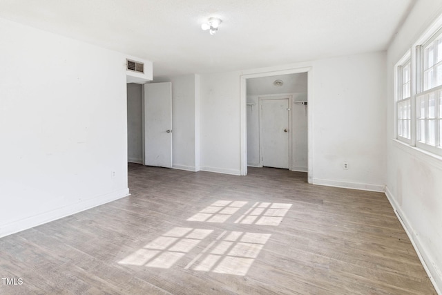 unfurnished room featuring light wood-style flooring, visible vents, and baseboards