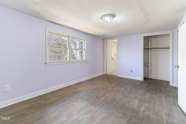 unfurnished bedroom with a closet, a textured ceiling, baseboards, and wood finished floors