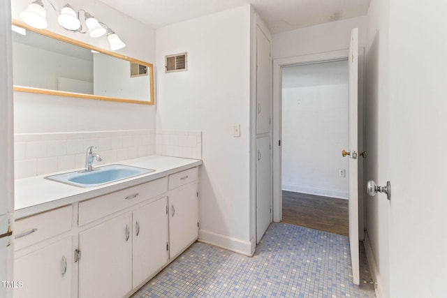 bathroom featuring vanity, baseboards, visible vents, tile patterned floors, and tasteful backsplash