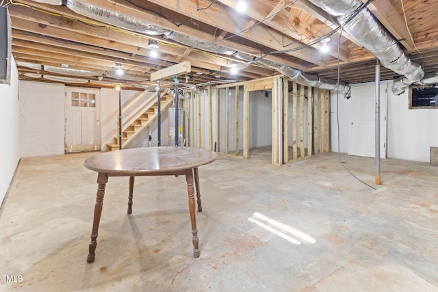 unfinished basement featuring stairs and water heater