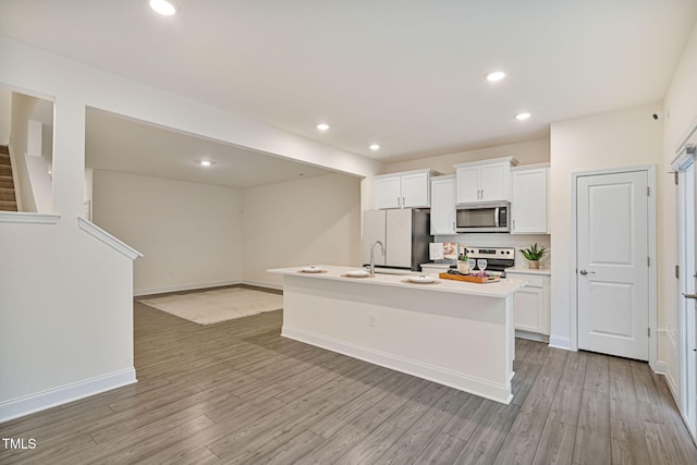 131 Wildflower Cir, Clayton, NC 27520 - kitchen with appliances with stainless steel finishes, white cabinetry, a center island with sink, light wood-style floors, and light countertops