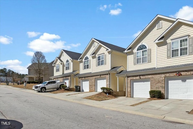 townhome / multi-family property featuring a residential view, brick siding, driveway, and an attached garage