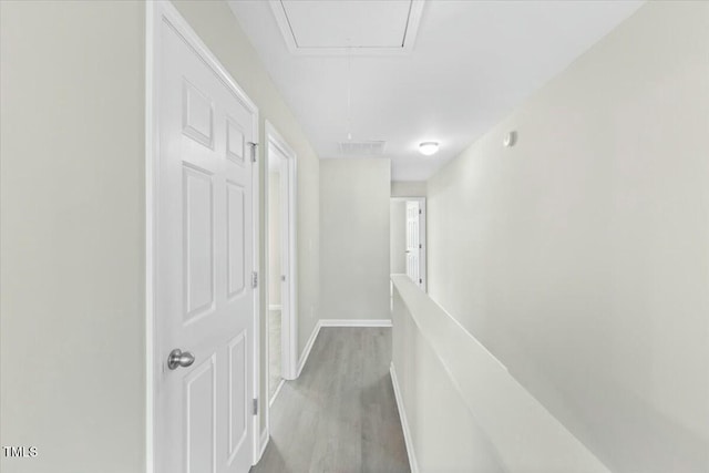 hall with attic access, visible vents, baseboards, an upstairs landing, and light wood-style floors