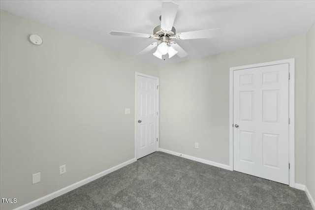 unfurnished bedroom featuring ceiling fan, dark colored carpet, and baseboards