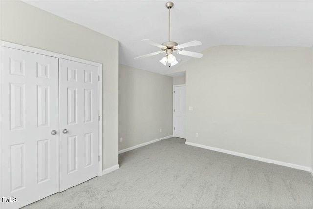 unfurnished bedroom with lofted ceiling, ceiling fan, baseboards, a closet, and carpet