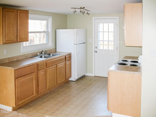 kitchen featuring cooktop, freestanding refrigerator, light countertops, light floors, and a sink