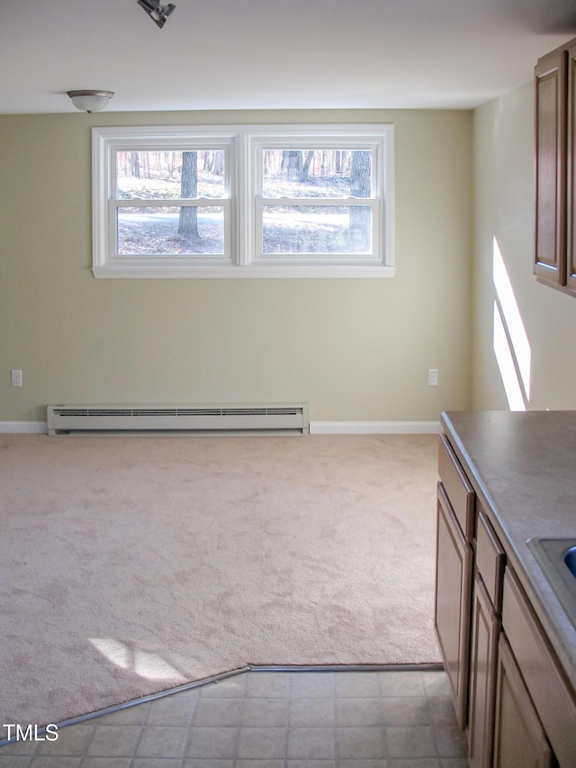 interior space featuring a baseboard heating unit, carpet flooring, and baseboards