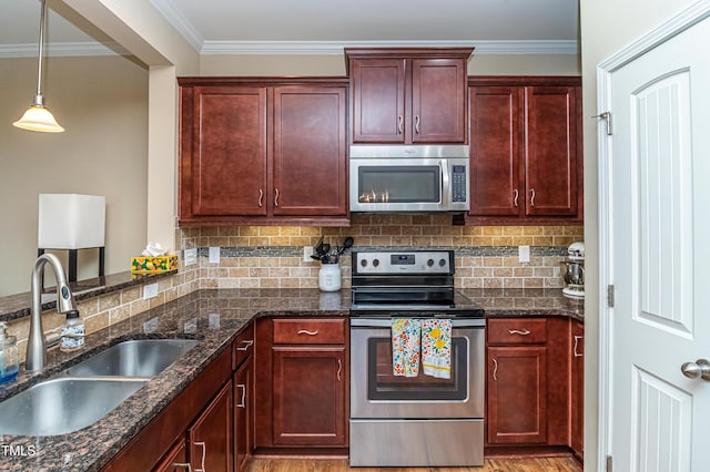 kitchen featuring decorative backsplash, reddish brown cabinets, appliances with stainless steel finishes, and a sink