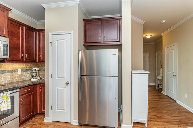 kitchen featuring baseboards, light wood finished floors, appliances with stainless steel finishes, crown molding, and backsplash