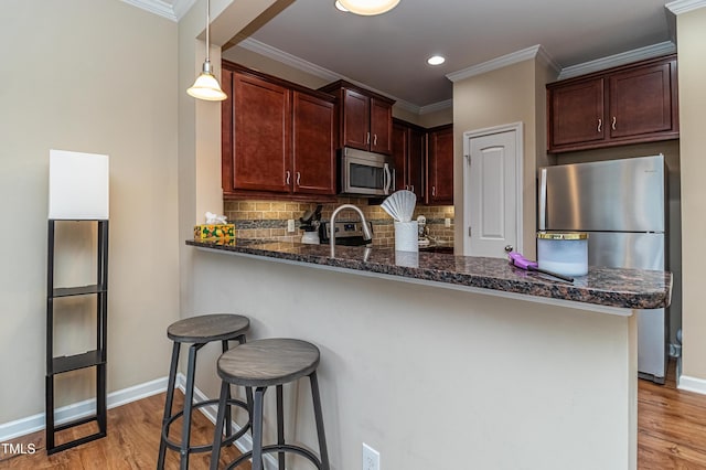 kitchen featuring backsplash, dark stone countertops, appliances with stainless steel finishes, and light wood-type flooring