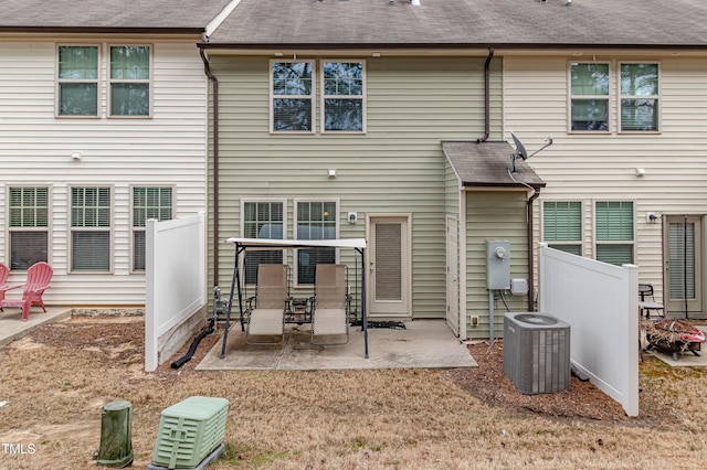 back of property with fence, central AC, a shingled roof, and a patio area