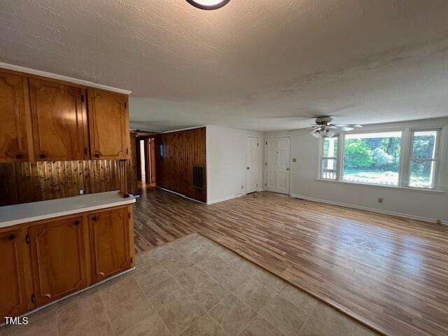 167 Chic Ennis Rd, Coats, NC 27521 - unfurnished living room featuring a ceiling fan, light floors, a textured ceiling, baseboards, and wood walls