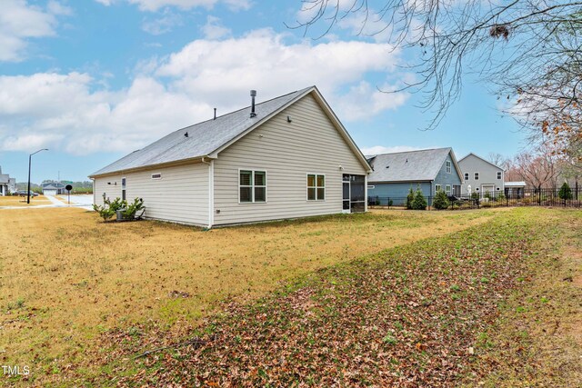 rear view of house with fence and a lawn