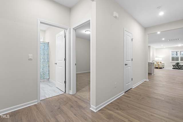 corridor featuring baseboards, visible vents, wood finished floors, and recessed lighting