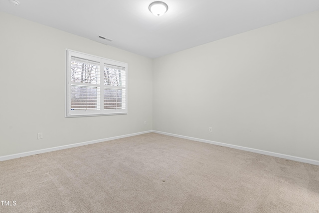 spare room with carpet floors, visible vents, and baseboards