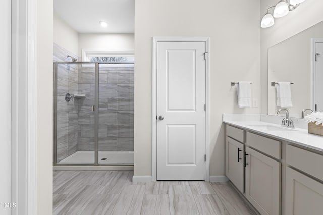 bathroom featuring baseboards, a shower stall, and vanity