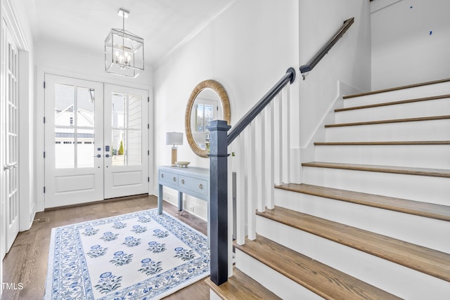 foyer featuring stairs, crown molding, wood finished floors, and a chandelier