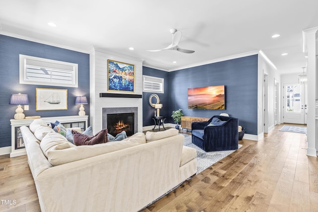 living area featuring hardwood / wood-style floors, baseboards, ornamental molding, and a fireplace