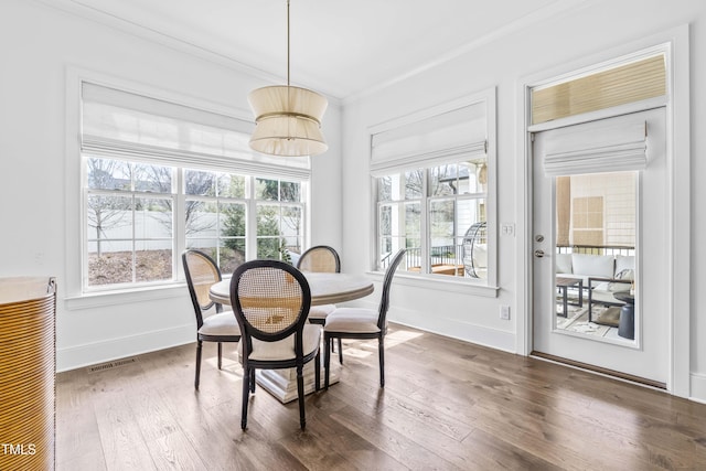 dining space featuring visible vents, hardwood / wood-style flooring, baseboards, and ornamental molding