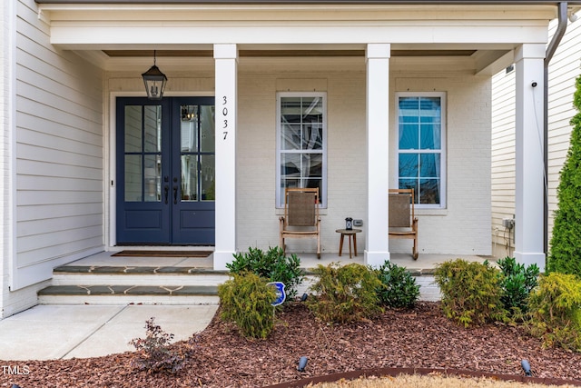 entrance to property featuring french doors, brick siding, and a porch