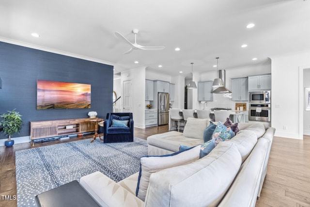 living area with recessed lighting, light wood-style floors, and ornamental molding