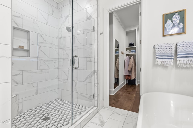 full bathroom featuring a soaking tub, ornamental molding, a shower stall, a spacious closet, and marble finish floor