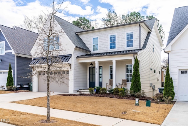 view of front of home with a standing seam roof, a porch, concrete driveway, and a garage