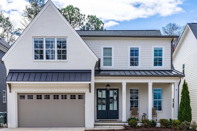 view of front of home with a porch, metal roof, driveway, and a standing seam roof