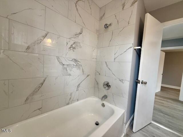 bathroom featuring baseboards, bathing tub / shower combination, and wood finished floors