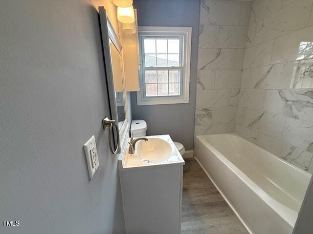 bathroom with vanity, toilet, wood finished floors, and baseboards