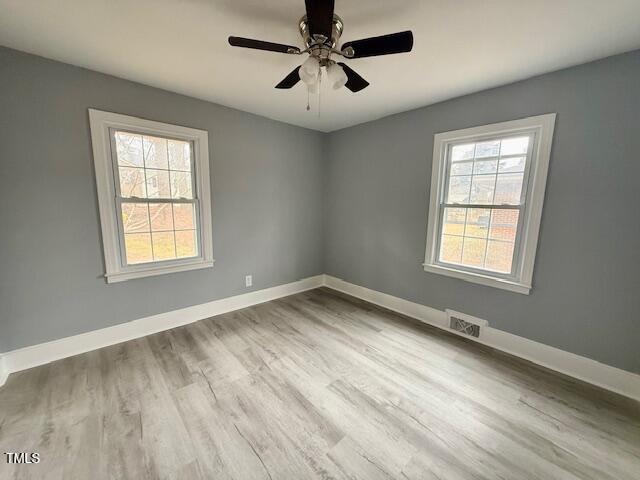 empty room with visible vents, baseboards, a healthy amount of sunlight, and wood finished floors