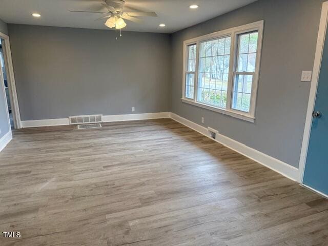 unfurnished room featuring recessed lighting, wood finished floors, visible vents, and baseboards