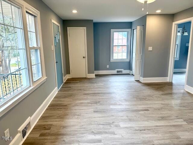 unfurnished room with visible vents, recessed lighting, wood finished floors, and baseboards